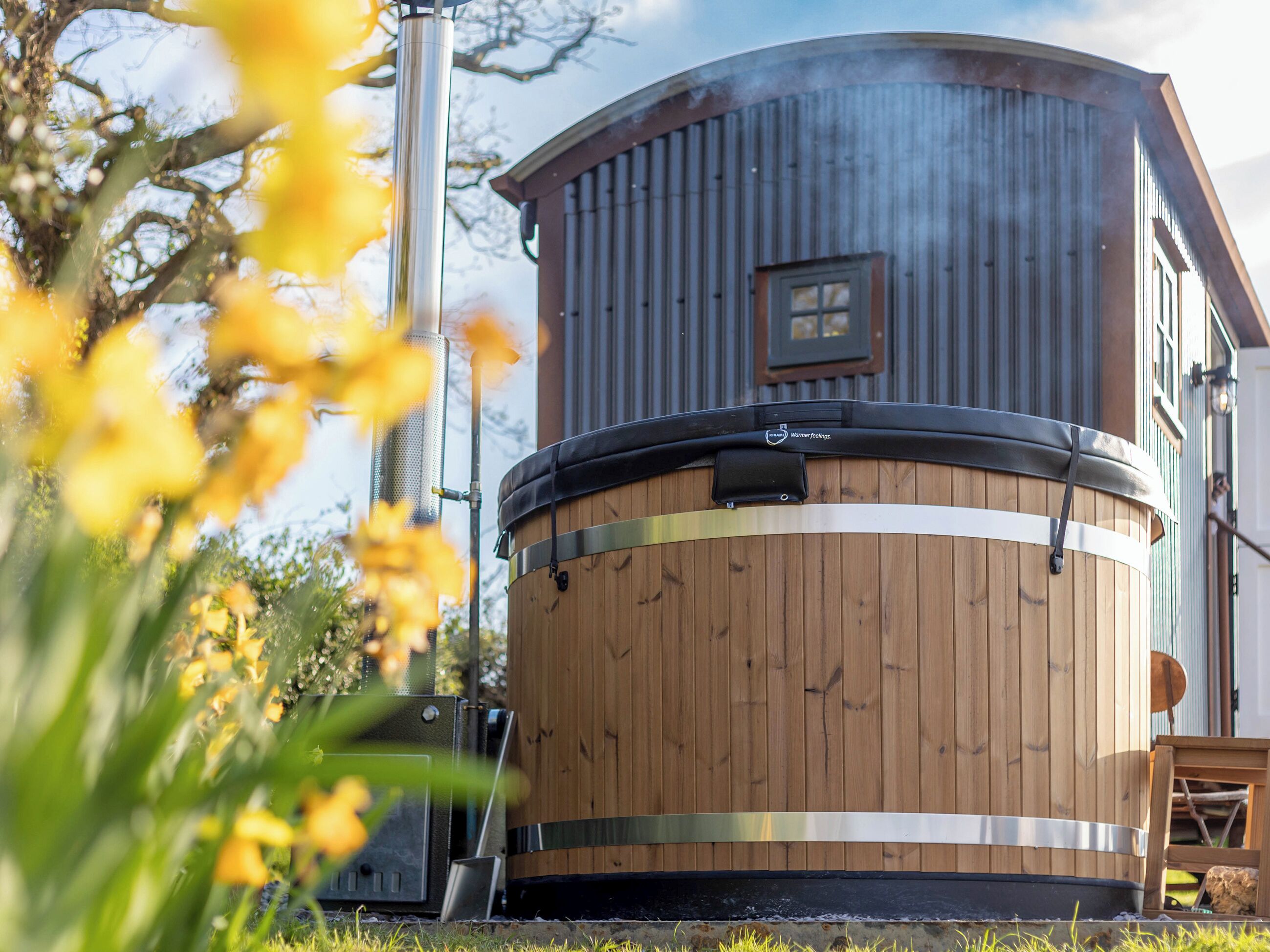 A wooden barrel-shaped building with a window, a metal structure, and a chair.