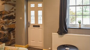 Et værelse med en stenvæg, en hvid dør med ruder, en radiator og et lille bord med en fjernbetjening.