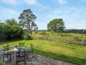 A patio with a glass table and chairs, surrounded by a wooden fence and trees. - North Star Apartment - UK3446 (Greenhaugh)