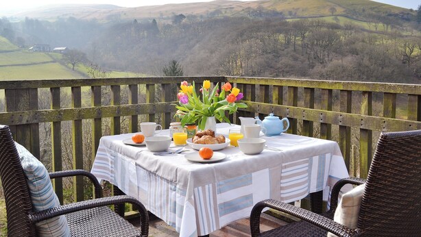 Une table dressée pour le petit-déjeuner, avec vue sur des collines verdoyantes.