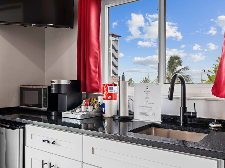 A modern kitchen with a microwave, coffee maker, and paper towel dispenser.