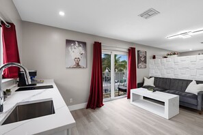 A modern living room with a grey sofa, white coffee table, and red curtains.
