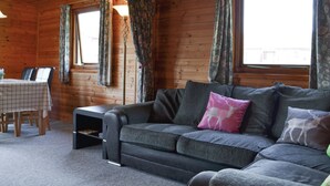 L'intérieur d'un chalet accueillant, avec un canapé, une table et des chaises.
