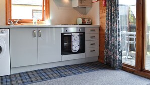 Une cuisine compacte équipée d’un lave-linge, d’un four et d’un grille-pain posés sur le plan de travail.