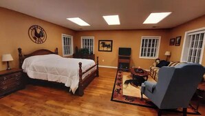 Un dormitorio con una cama grande, una silla, un aparador y un televisor.