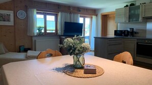 Una habitación acogedora con una mesa de comedor, sillas, televisor y una zona de cocina con electrodomésticos.