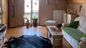 Una habitación acogedora con paredes de madera, un sofá blanco, un tapete negro y un armario de madera.