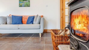 Ein Wohnzimmer mit einer Couch, einem Gemälde, einem Kamin und einem Korbwäschesammler.