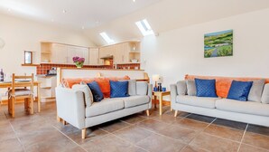 Ein modernes Wohnzimmer mit zwei Sofas, einem Esstisch und einer Küche im Hintergrund.