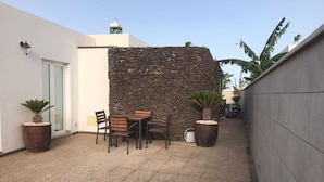 Un espace extérieur aménagé avec un mur en pierre, une table entourée de chaises et des plantes en pot.