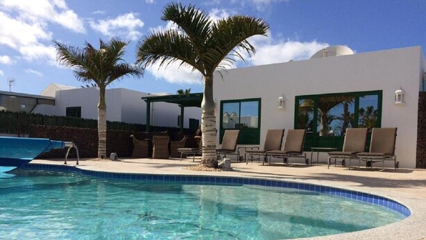 Une piscine avec des chaises longues et des palmiers.