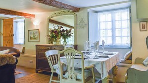 Un comedor con una mesa preparada para cuatro, un espejo sobre la mesa y una ventana con cortinas.