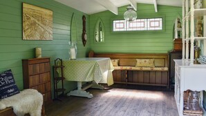 Una habitación con un banco de madera, una mesa con mantel de lunares, una pared verde y una ventana con diseño de vitral.
