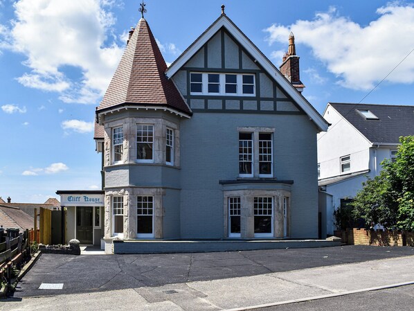 A traditional Tudor-style house with a prominent tower, bay windows, and a well-maintained facade. - 8 bedroom accommodation in Swanage (Swanage)