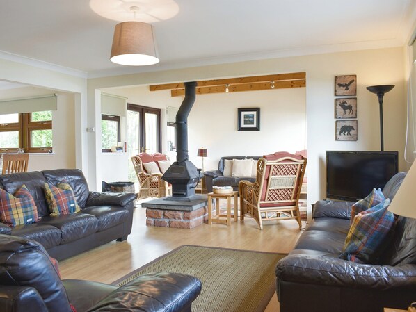Una sala de estar con sofás de cuero, chimenea, sillones de mimbre y televisor.