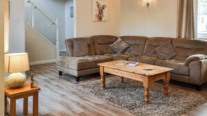 Ein Wohnzimmer mit einer braunen Ledersofa, einem Holztisch und einem gemusterten Teppich.