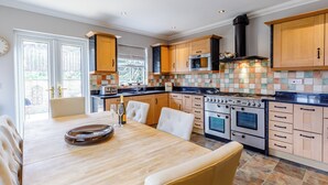 A modern kitchen with a dining area, featuring a large stove, oven, and microwave. - 3 bedroom accommodation in Alnmouth (Alnmouth)