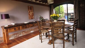 Comedor con mesa y sillas de madera, una lámpara y un florero con flores.