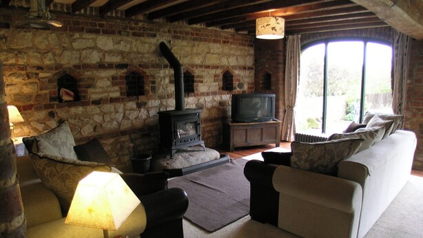 Una sala de estar acogedora con chimenea de piedra, televisión y asientos cómodos.