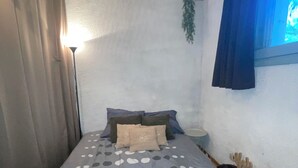 Une chambre à coucher avec un lit, des rideaux, une table de chevet, une lampe et une fenêtre donnant sur un beau paysage.