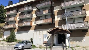 Un immeuble à plusieurs étages doté de balcons, d’une entrée couverte et d’une voiture garée.
