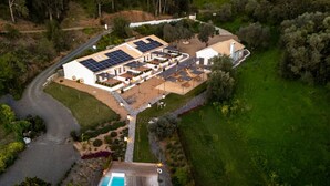 An aerial view of a property with a swimming pool, solar panels, and a large building with multiple rooms.