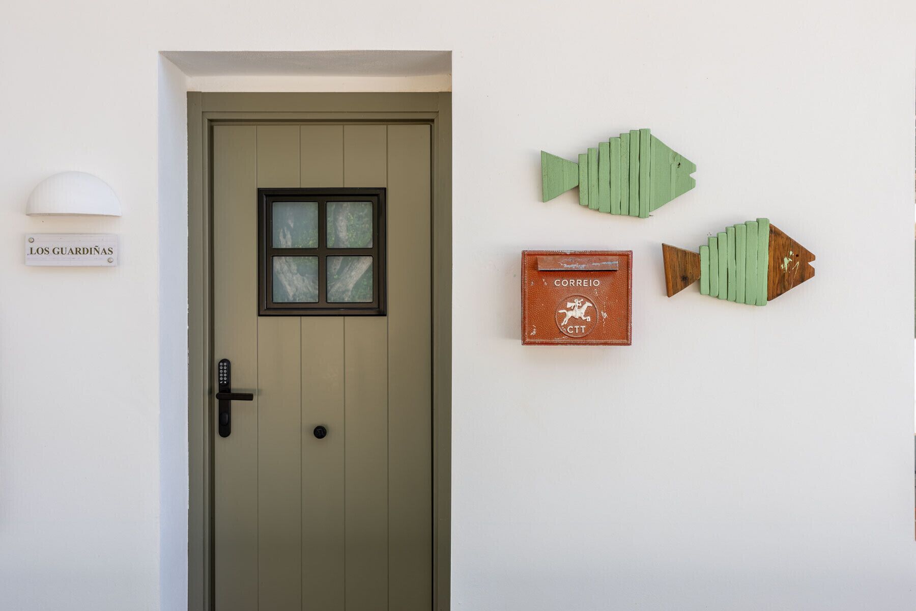 A door with a window and a mailbox on the wall.