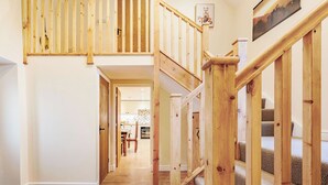 A wooden staircase with a view of a kitchen and dining area in the background. - 2 bedroom accommodation in Penybntfawr, near Oswestry (Penybntfawr, near Oswestry)