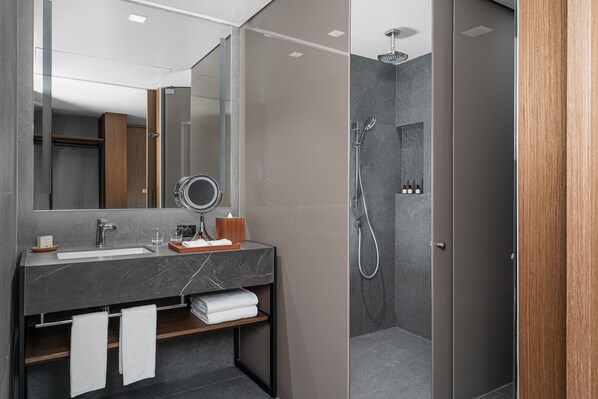 A modern bathroom with a marble sink, a mirror, and a shower area.
