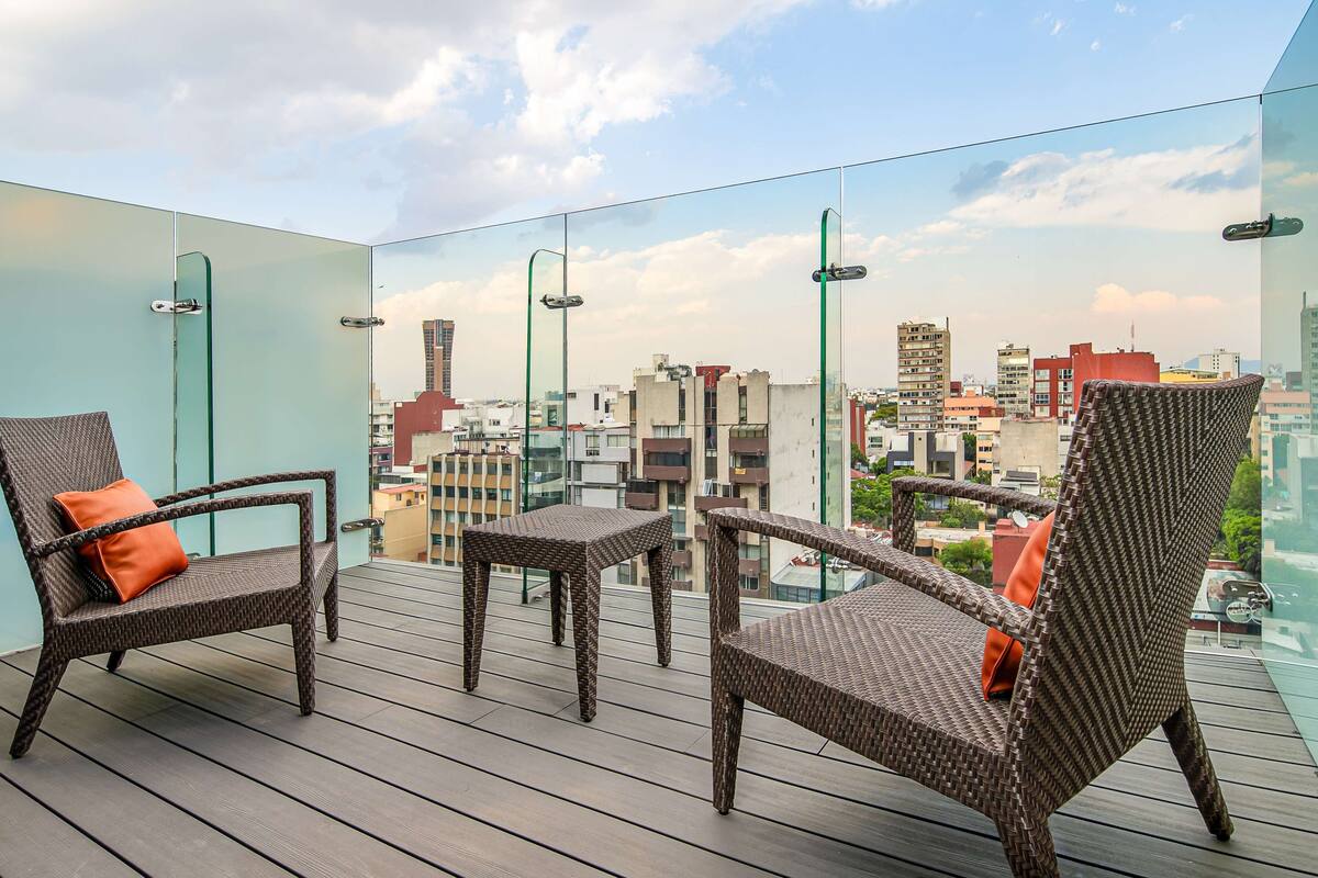 A balcony with wicker furniture and a city view.