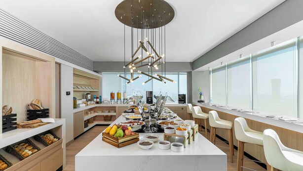 A modern kitchen with a central island, various food items, and a unique hanging light fixture.