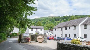 A rural street with a stone wall, a sign for Quaysiders Apartments & Hotel Rooms, and parked cars. - Quaysiders Club B - UK34758 (Ambleside)