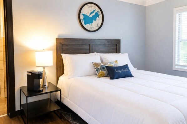 A hotel room with a bed, a nightstand, a lamp, a coffee maker, and a wall map.