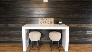 A white desk with a sign reading 'Motel Office' and two stools.