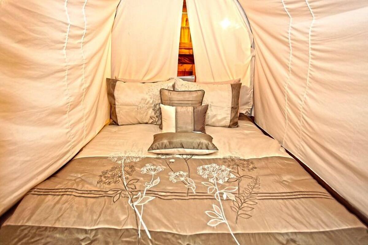 A bed with a canopy, pillows, and a floral bedspread.