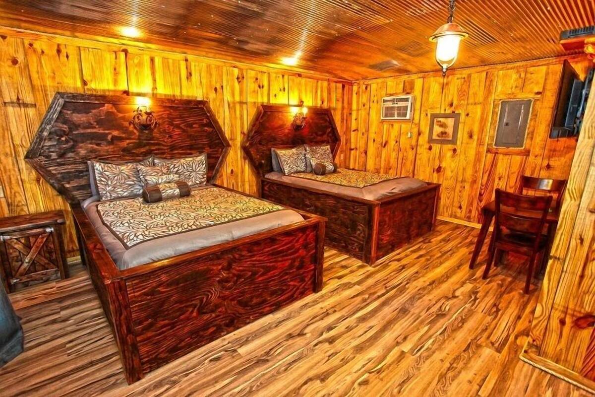 A rustic wooden room with two beds, a small table, and a chair.