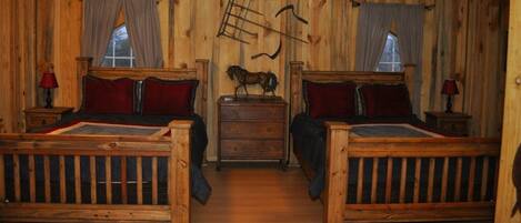 A wooden cabin-style room with two beds, a dresser, and a horse figurine on the wall.
