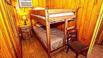 A bunk bed room with wooden walls and a small bedside table with a lamp.