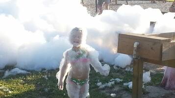Un niño cubierto de espuma en un parque infantil.
