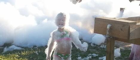 Un niño cubierto de espuma en un parque infantil.