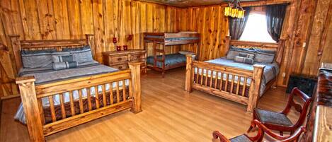 Una habitación rústica de madera con dos literas, un aparador de madera, una silla y una ventana con cortinas.