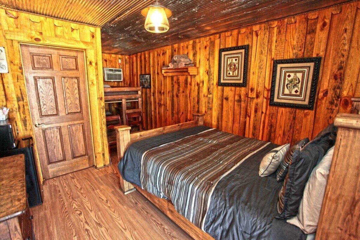 Una habitación de madera con una cama, un escritorio y una silla.