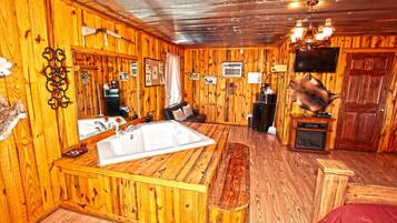 A wooden interior with a large bathtub, a television, and a fireplace.
