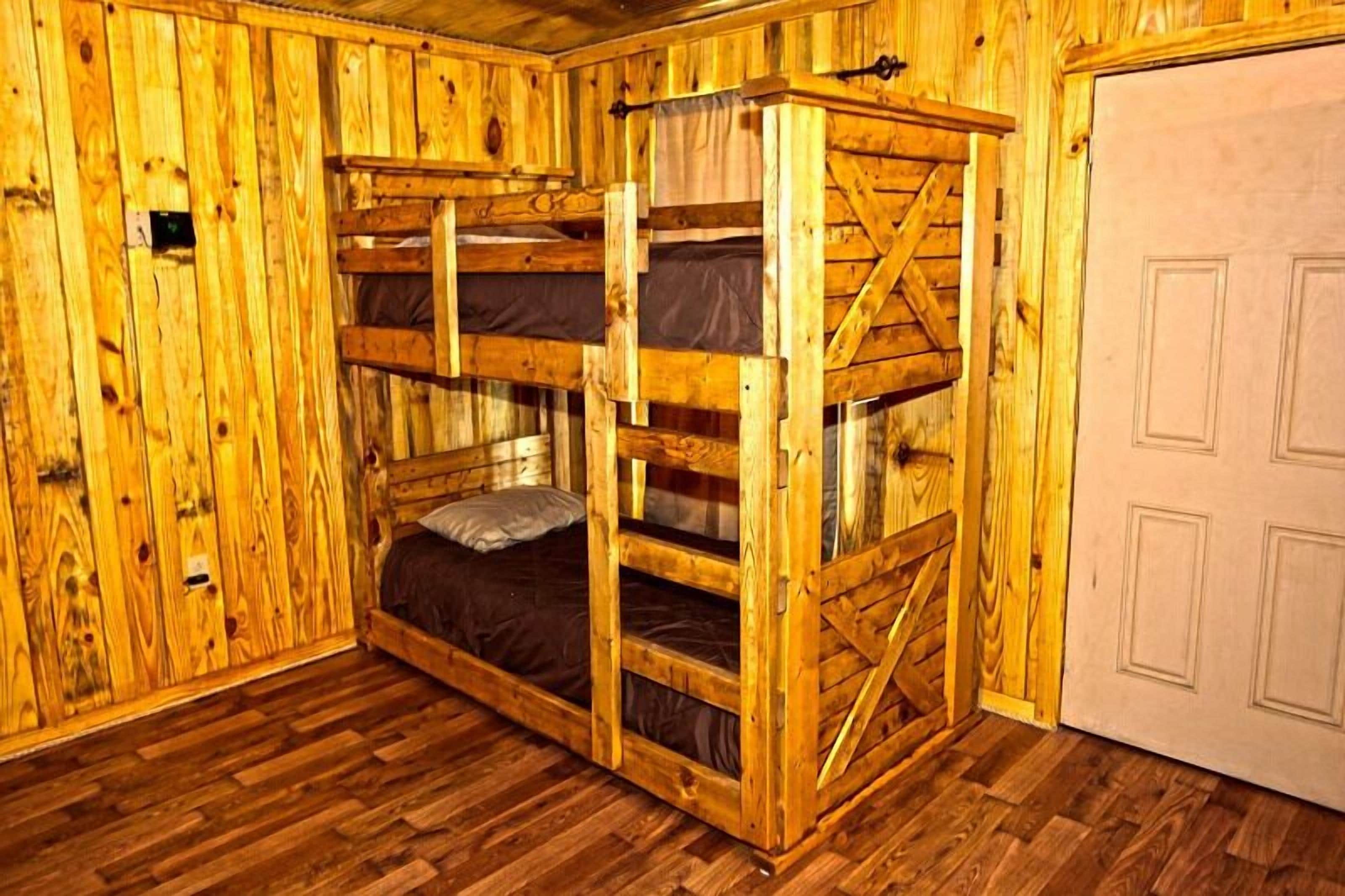 A wooden bunk bed room with a door and wooden walls.