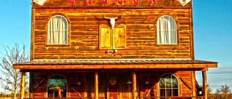 A wooden saloon with a prominent sign, two windows, and a front porch.