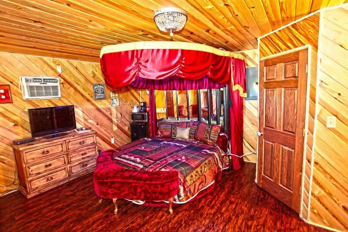 A wooden-paneled room with a bed, a television, and a wardrobe.