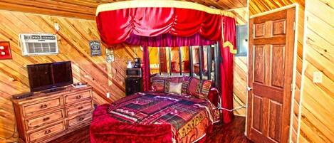 Een kamer met houten lambrisering, een bed, een televisie en een garderobe.