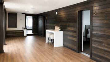 A hotel lobby with a reception desk, a staircase, and a dark wooden wall.