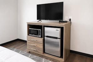 A modern kitchenette with a microwave, refrigerator, and flat-screen TV on a wooden cabinet. - The Queen of Adventure Near Downtown Muskegon (Muskegon)