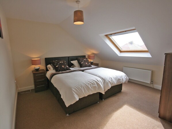 A bedroom with a bed, bedside lamps, a radiator, and a skylight. - 3 bedroom accommodation in Amble (Amble)